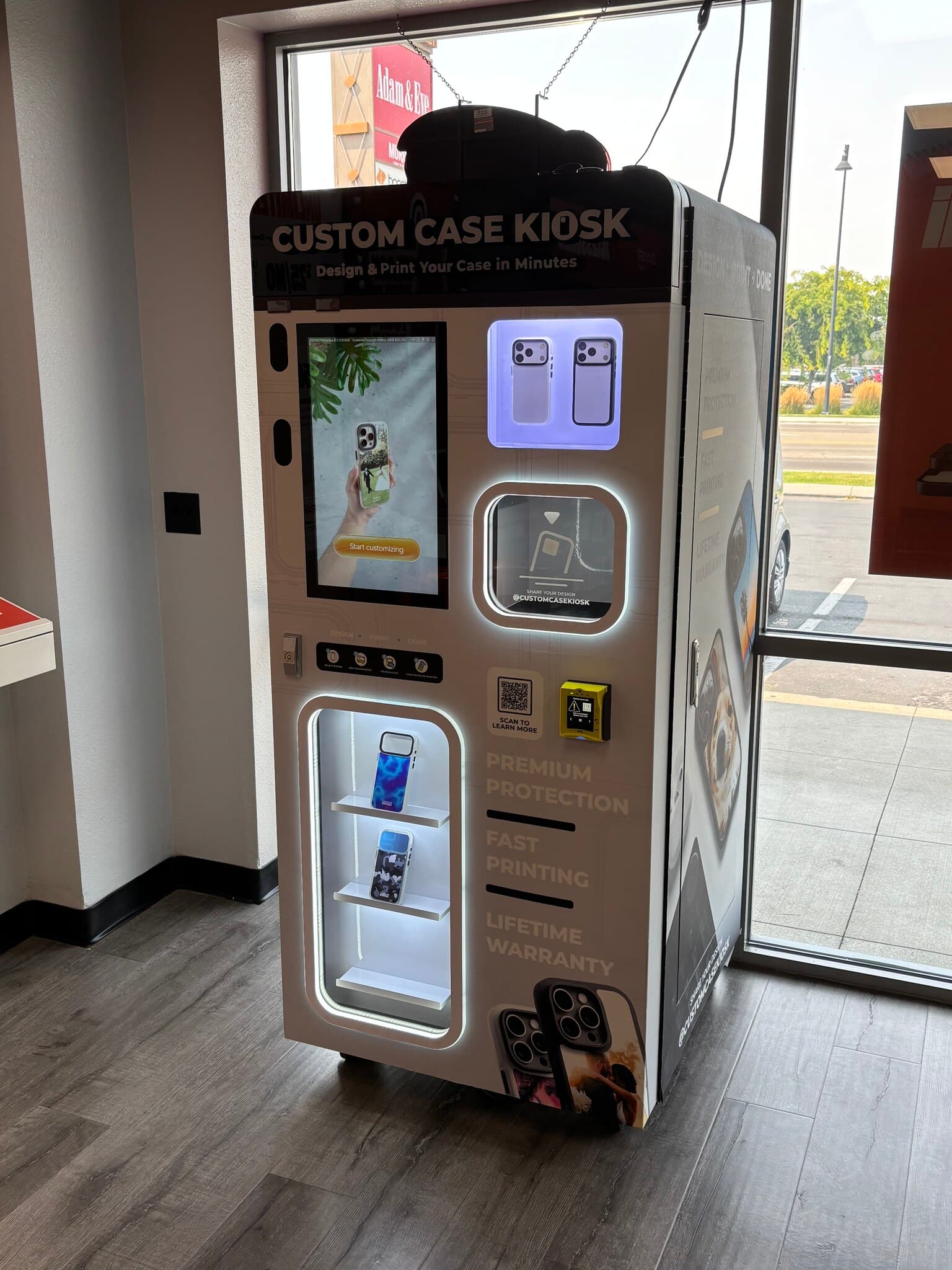 Custom Case Kiosk inside Boost Mobile on Garrity Blvd in Nampa, Idaho — the kiosk beside the storefront window, attract screen lit and printed cases on the display shelves