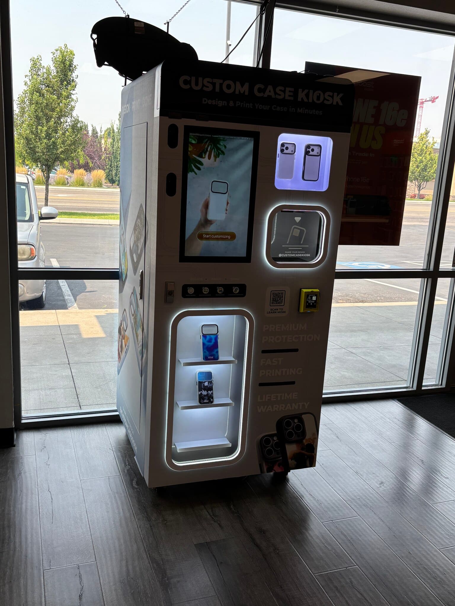Custom Case Kiosk in Nampa, ID — angled view of the touchscreen, case pickup window and backlit case shelves against the store's front windows