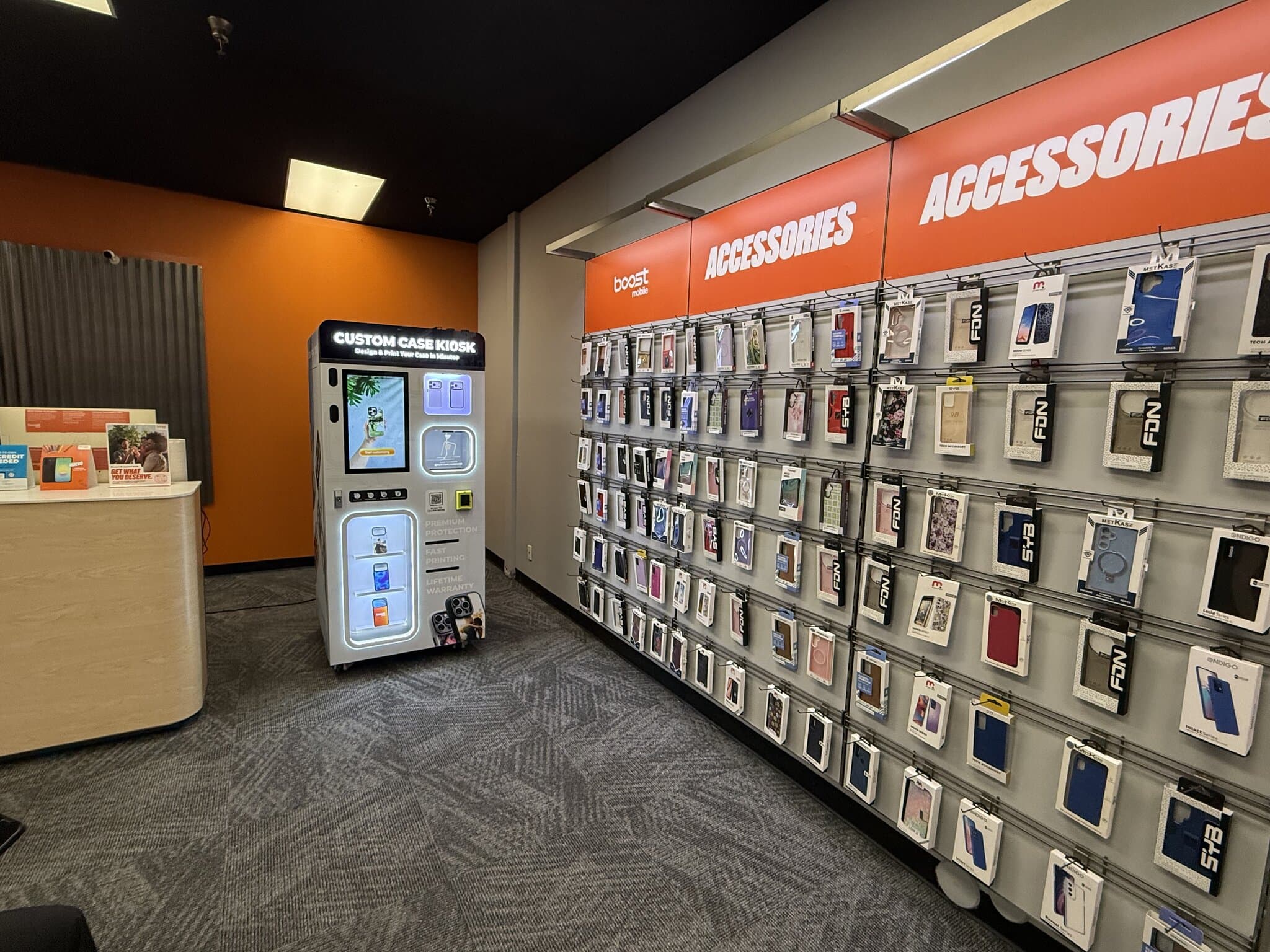Custom Case Kiosk beside the Boost Mobile accessories wall in Phoenix, AZ, with rows of phone cases on display