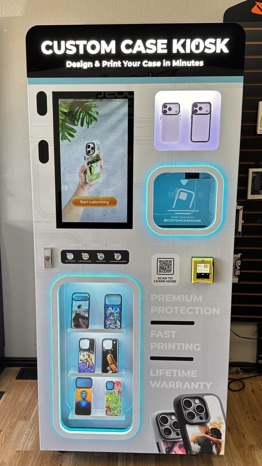 The front of the Custom Case Kiosk at Boost Mobile in Salt Lake City, its touchscreen showing the Start customizing screen above the tap-to-pay reader and a shelf of sample printed cases